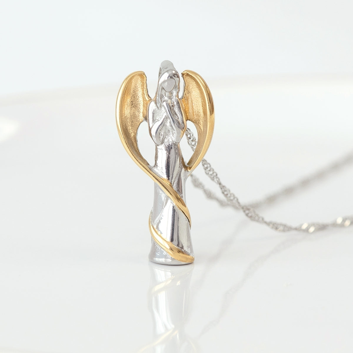 Close-up of guardian angel memorial urn pendant with gold-tone wings and stainless steel design