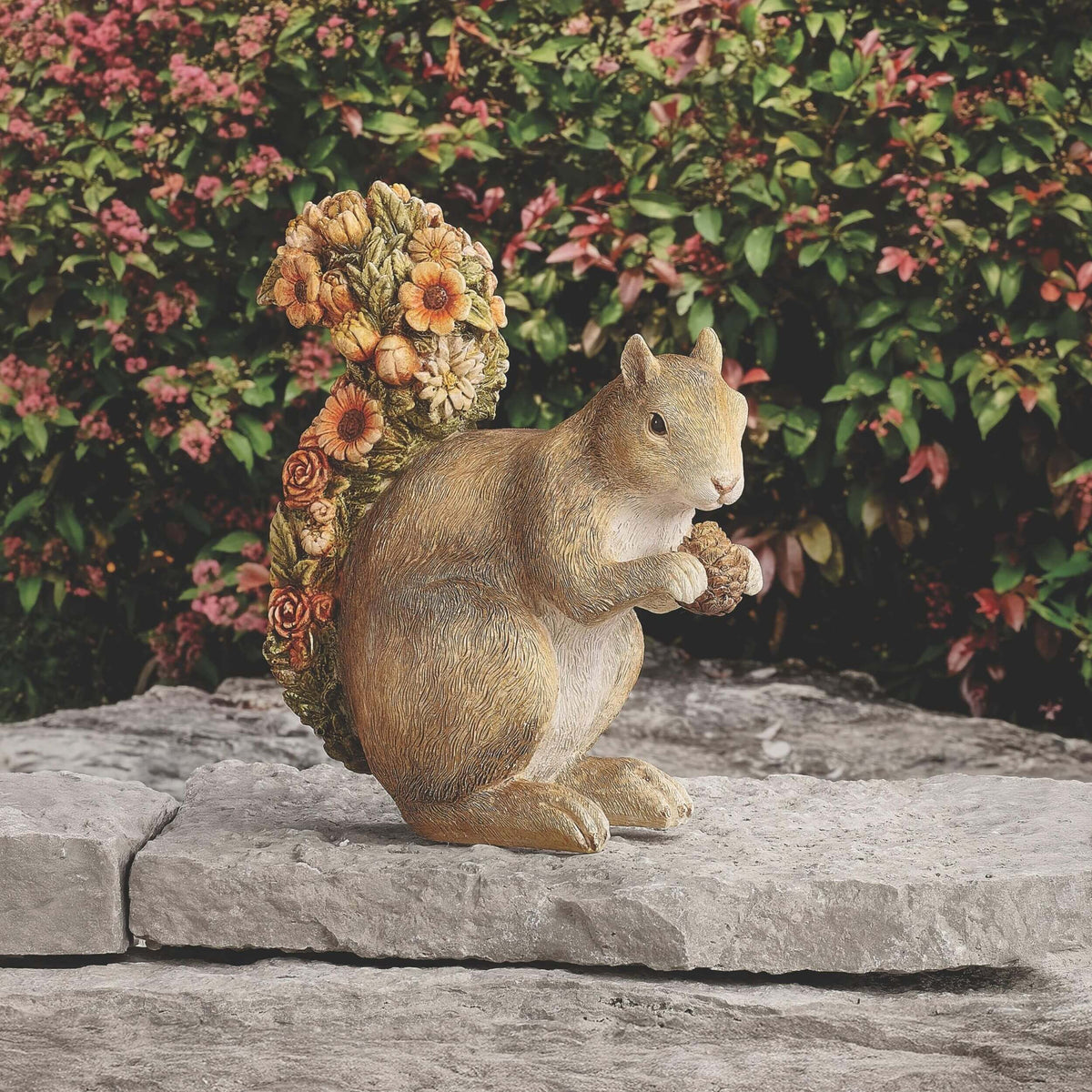 Squirrel with floral tail decorative garden sculpture in outdoor setting