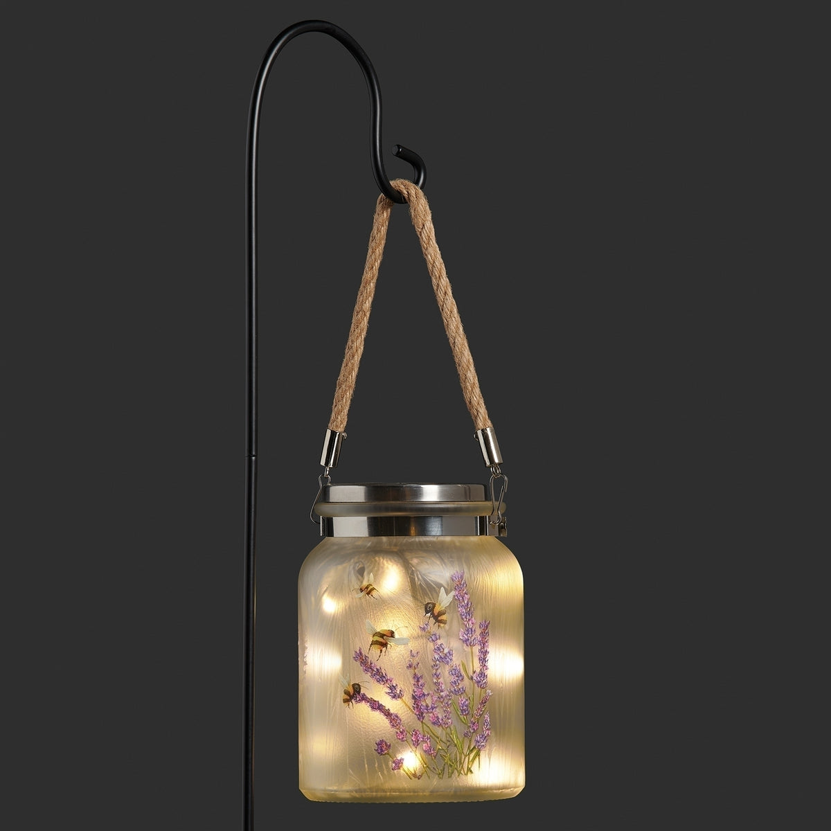 Illuminated solar garden jar with lavender design hanging at night