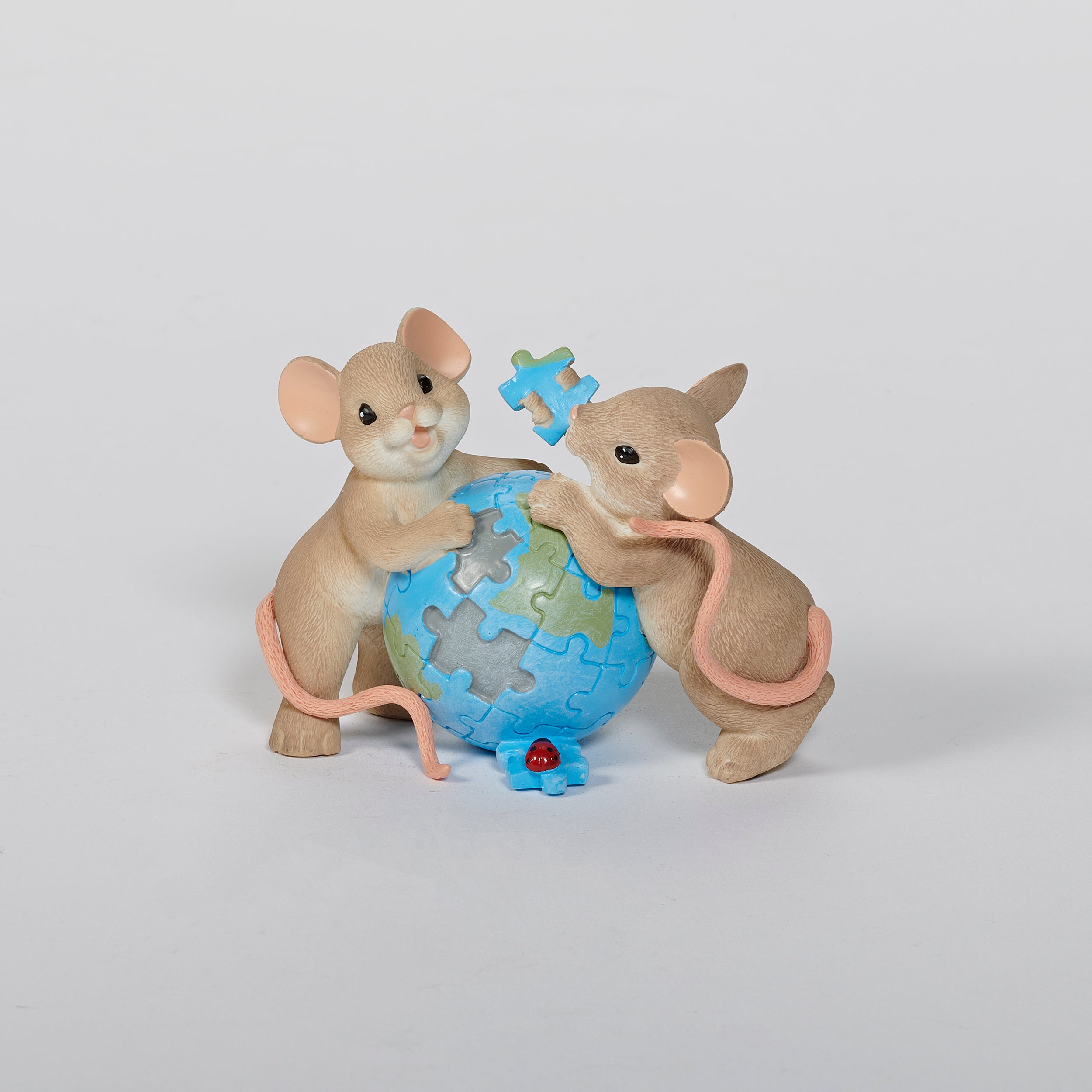 Two mouse figurines holding a globe puzzle