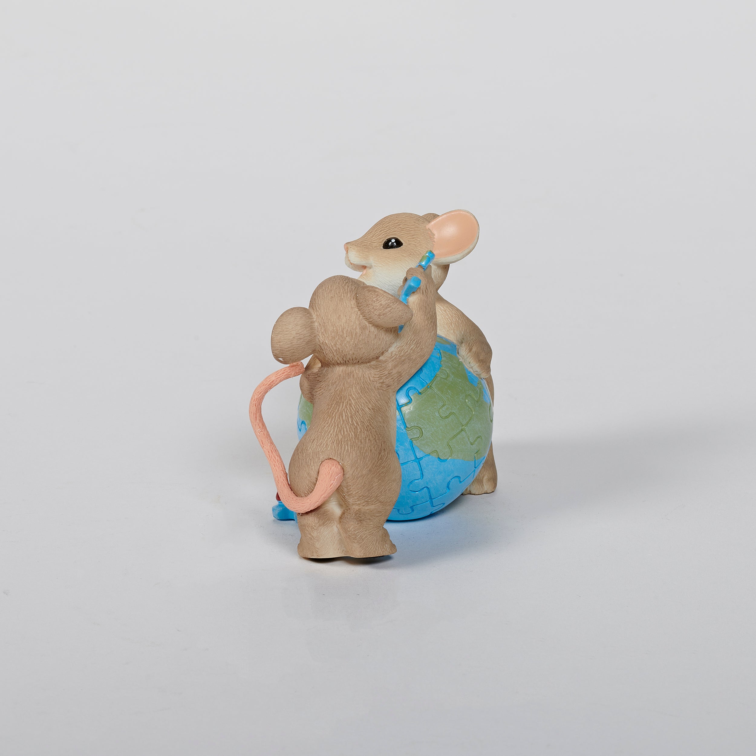 Two mouse figurines holding a globe puzzle