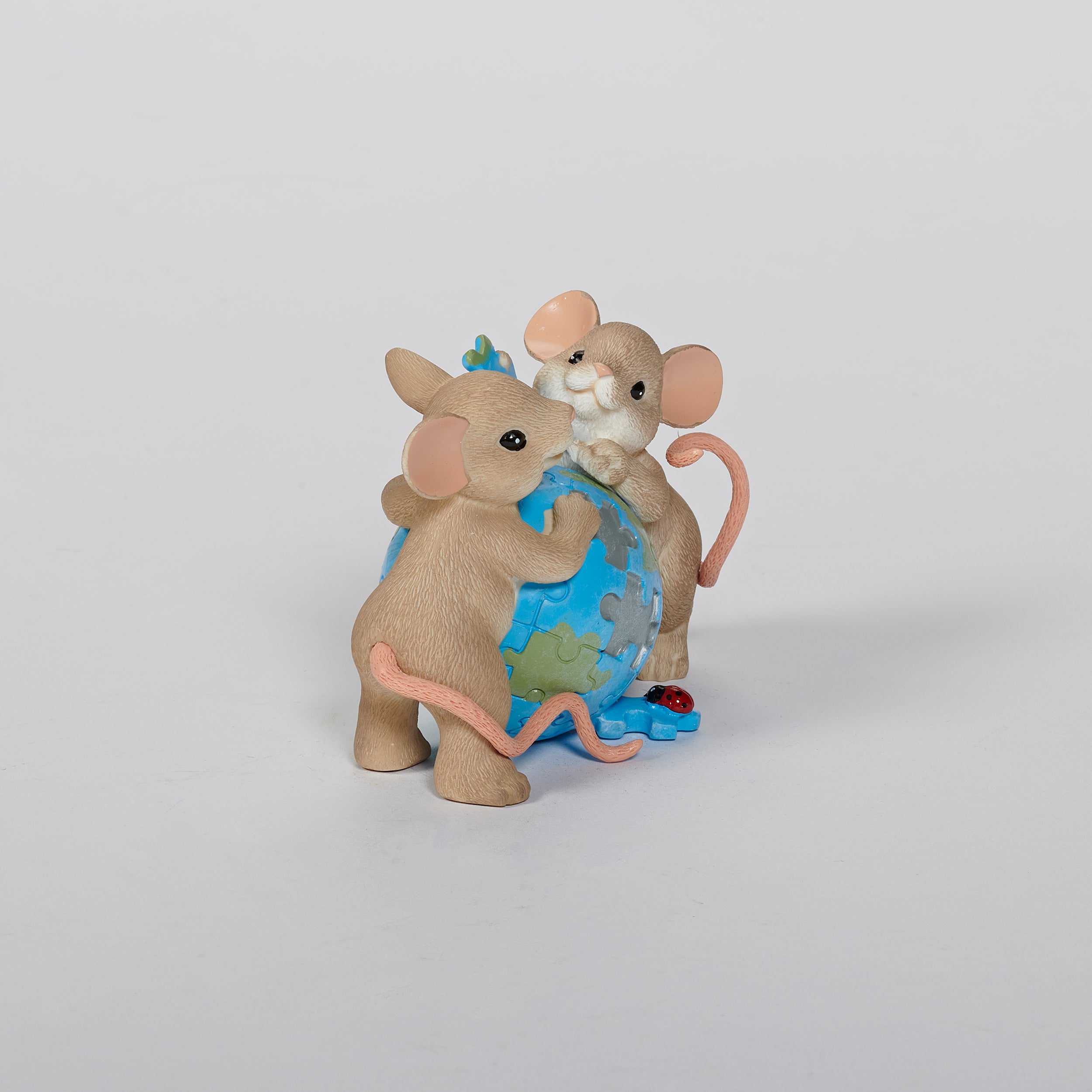 Two mouse figurines holding a globe puzzle