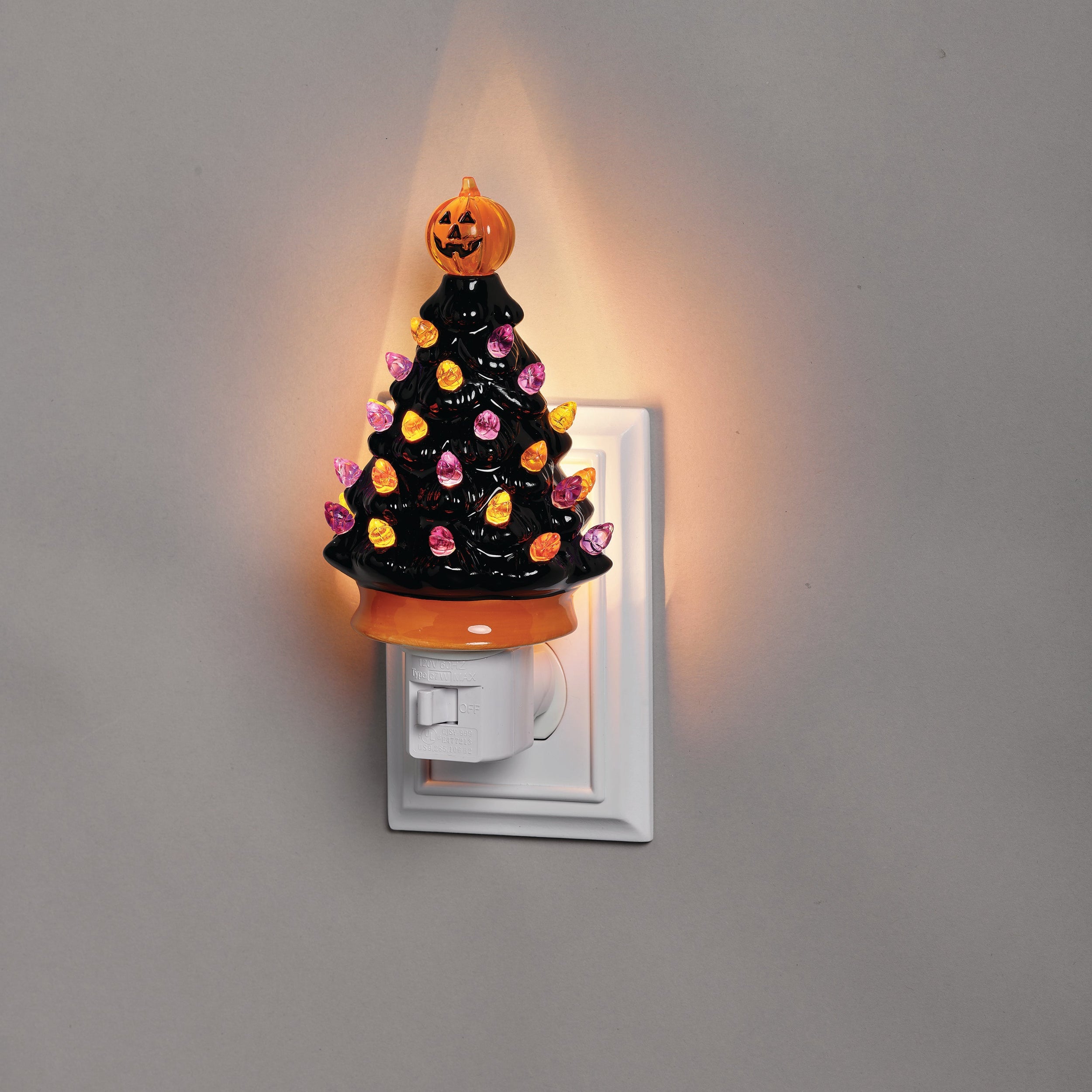 Halloween-themed night light with a pumpkin on top, attached to a wall outlet.