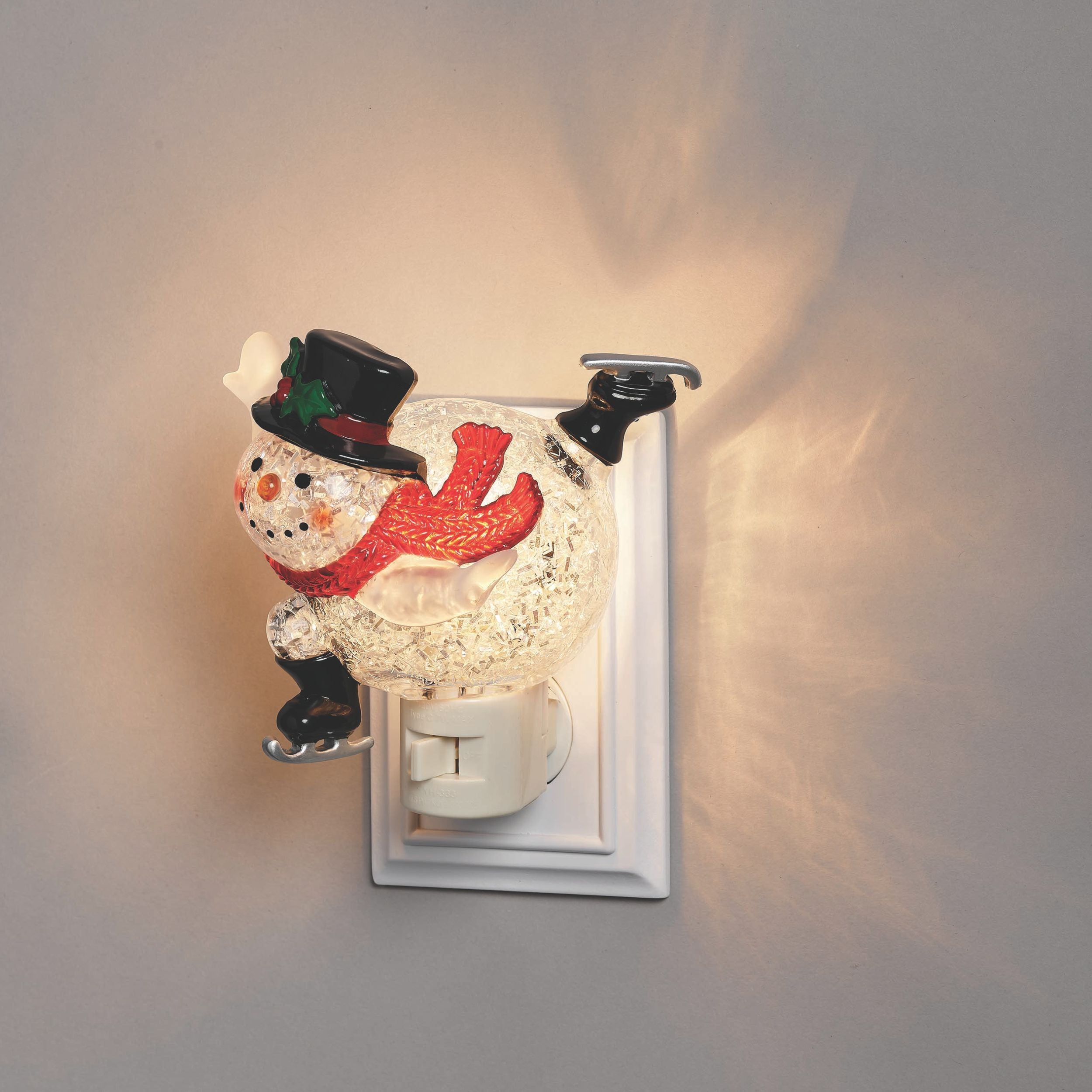 Decorative night light shaped like a snowman with a top hat on a gray wall.