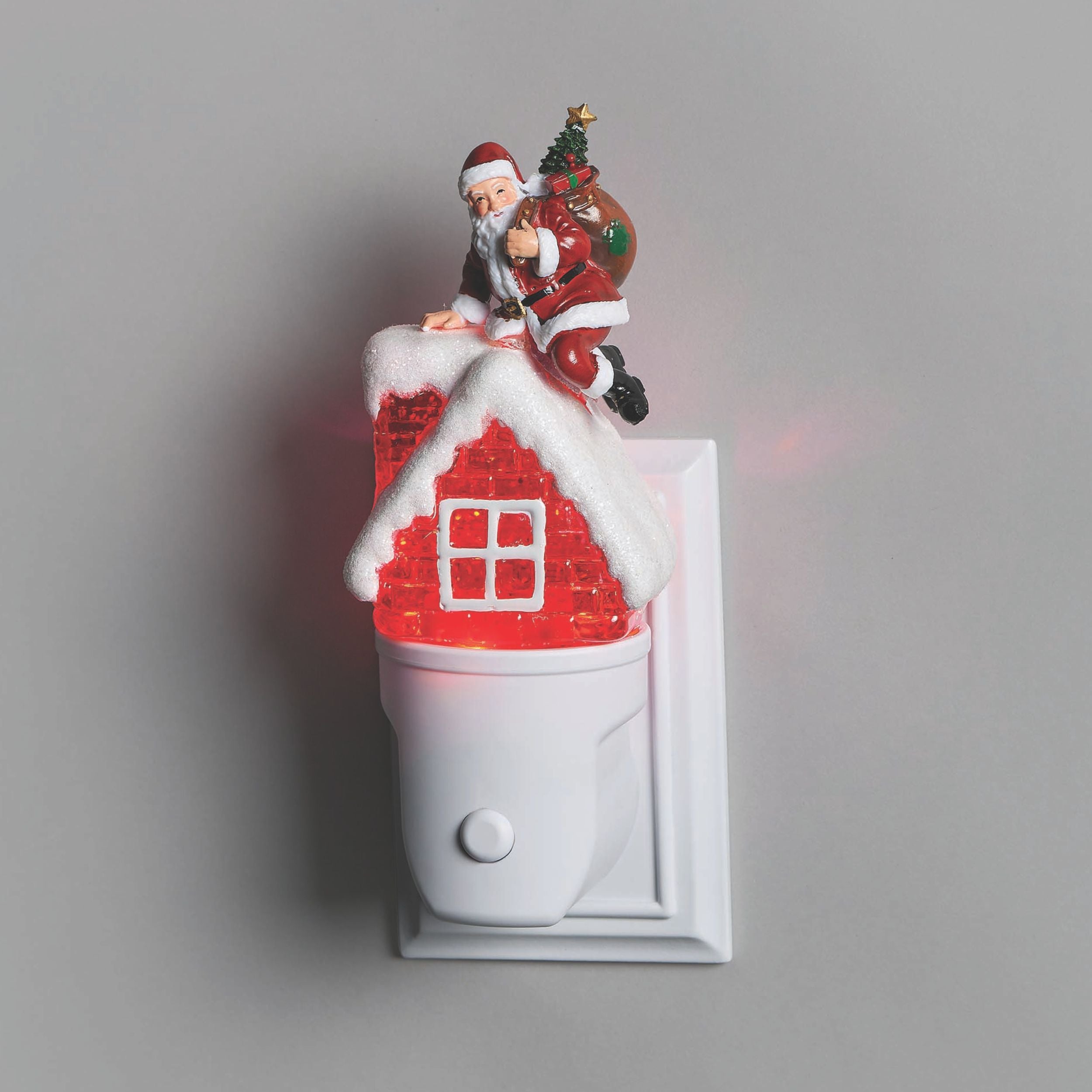 Decorative night light with Santa Claus on a roof and tree, on a plain background