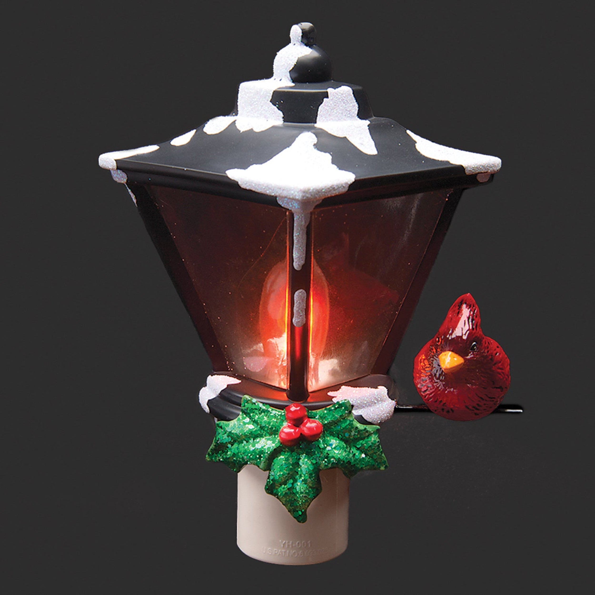 Decorative Christmas lamp with red light, snow, and holly leaves on a black background