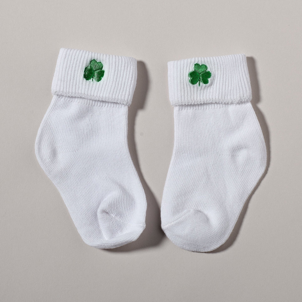 White baptism baby socks featuring small green shamrock embroidery