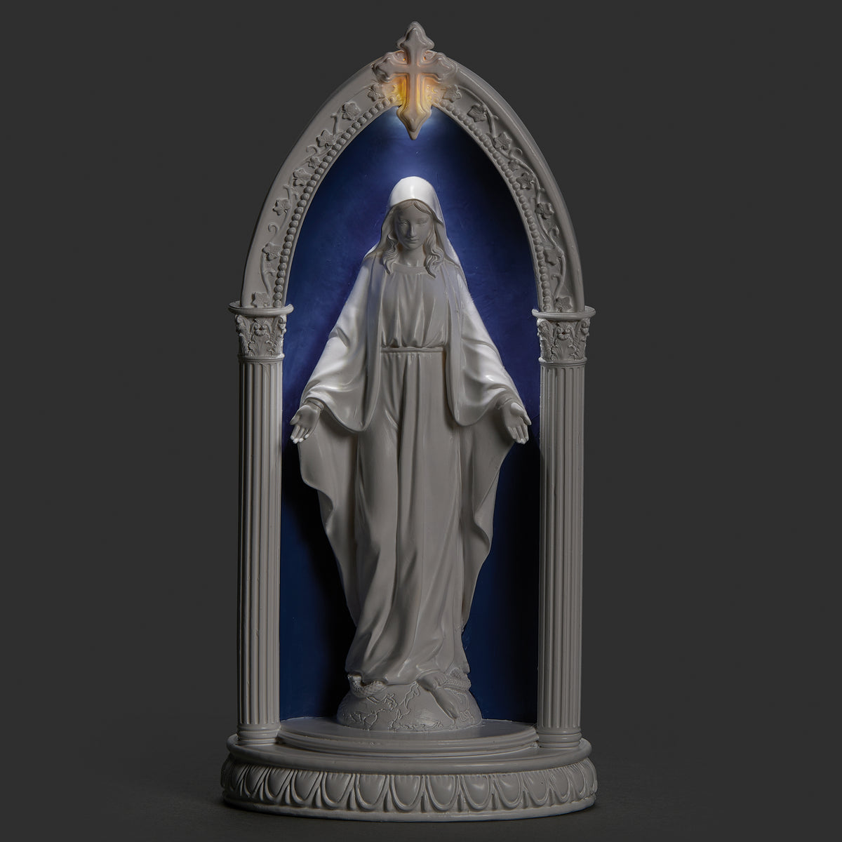 Lighted view of Our Lady of Grace in Arch plaque glowing softly around Mary within the blue arched frame