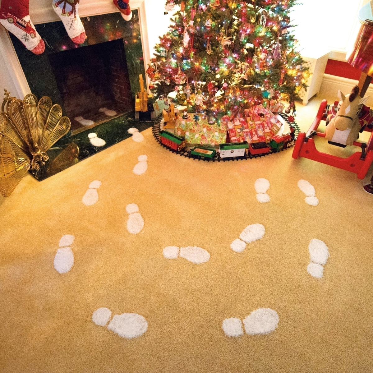 Trail of white artificial snow footprints across a carpet leading toward a decorated Christmas tree.