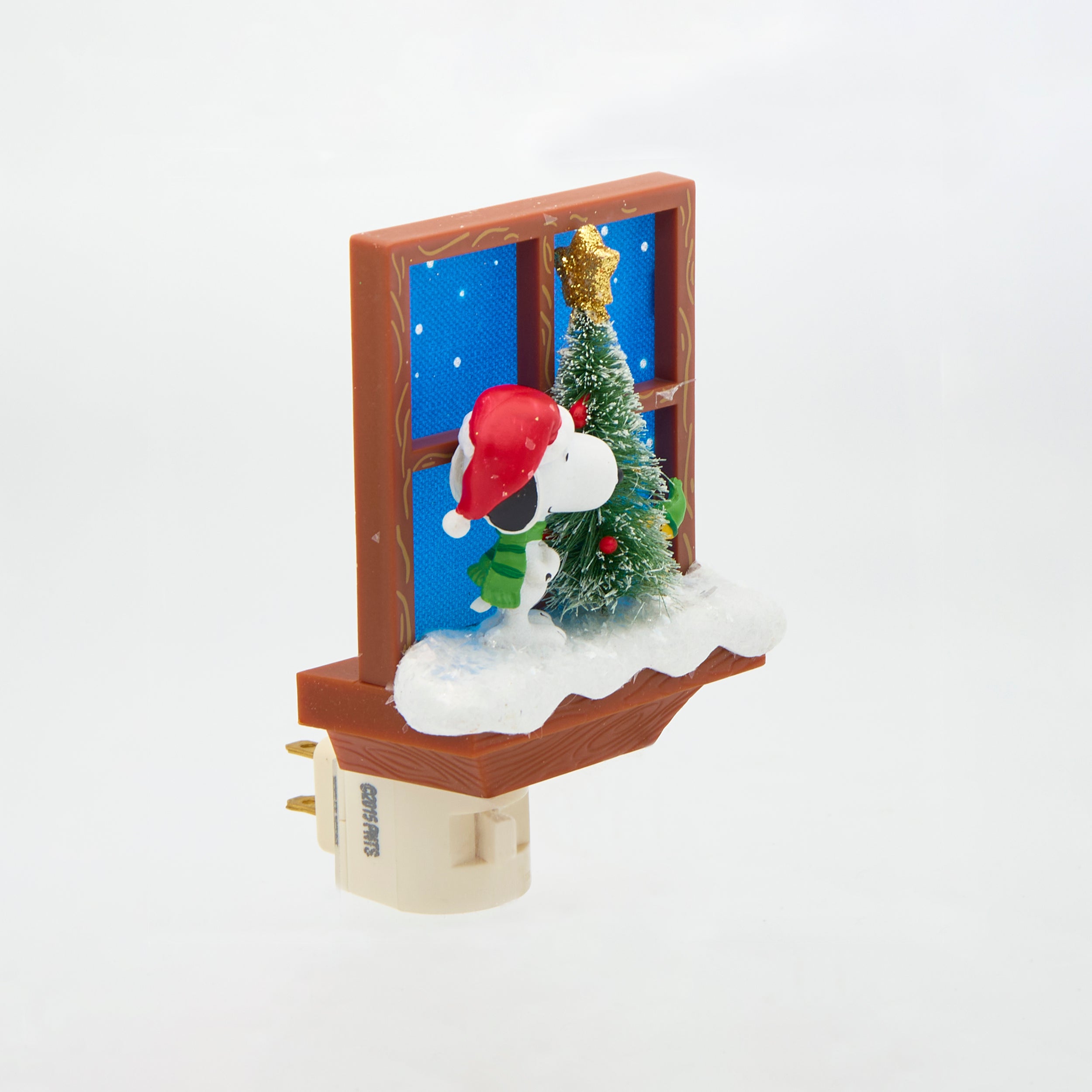 Decorative night light with Snoopy, Woodstock, and a Christmas tree in front of a window.