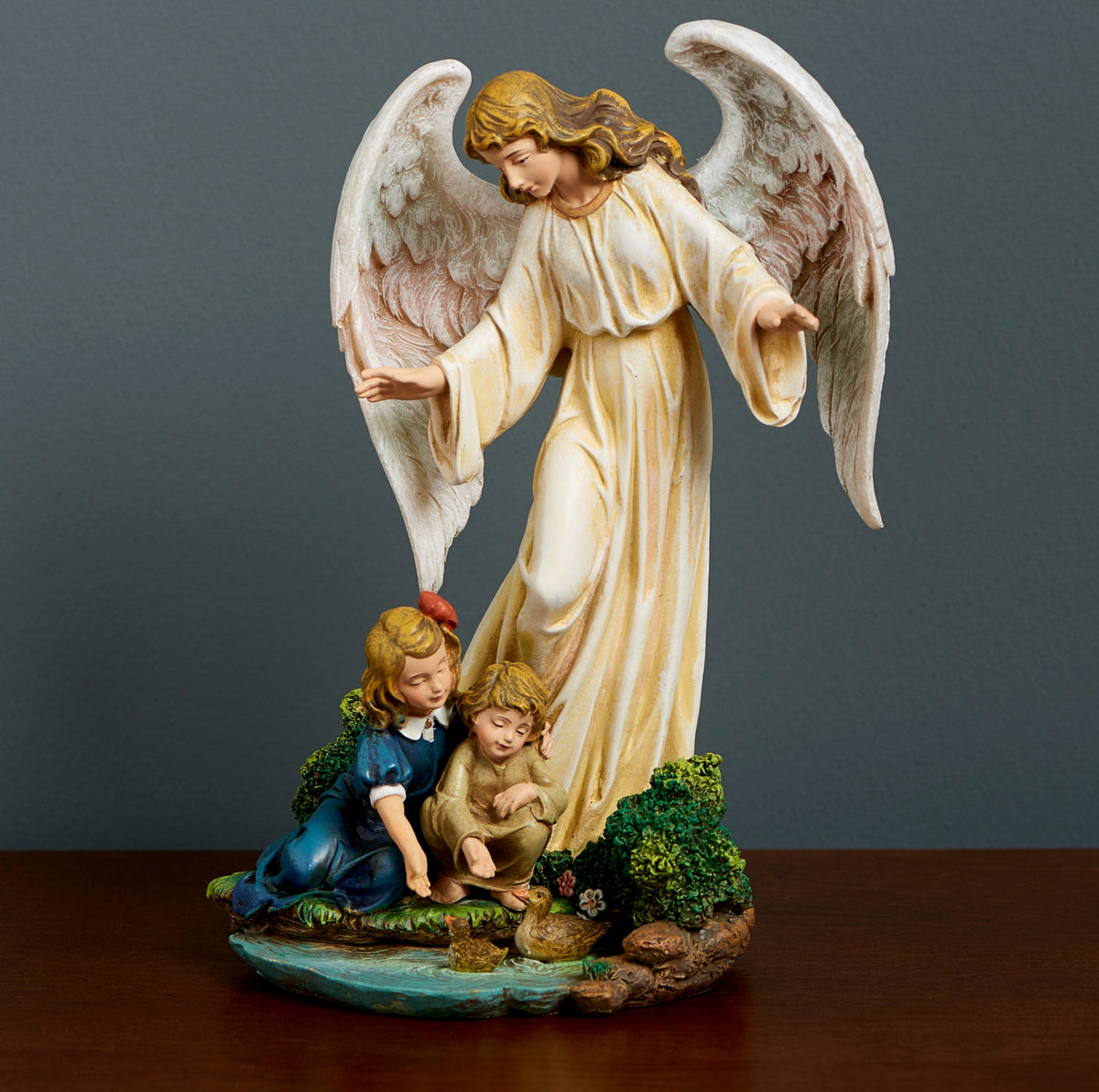 Joseph's Studio Guardian Angel with Child Figure featuring a standing angel with large feathered wings watching over two children seated beside a stream