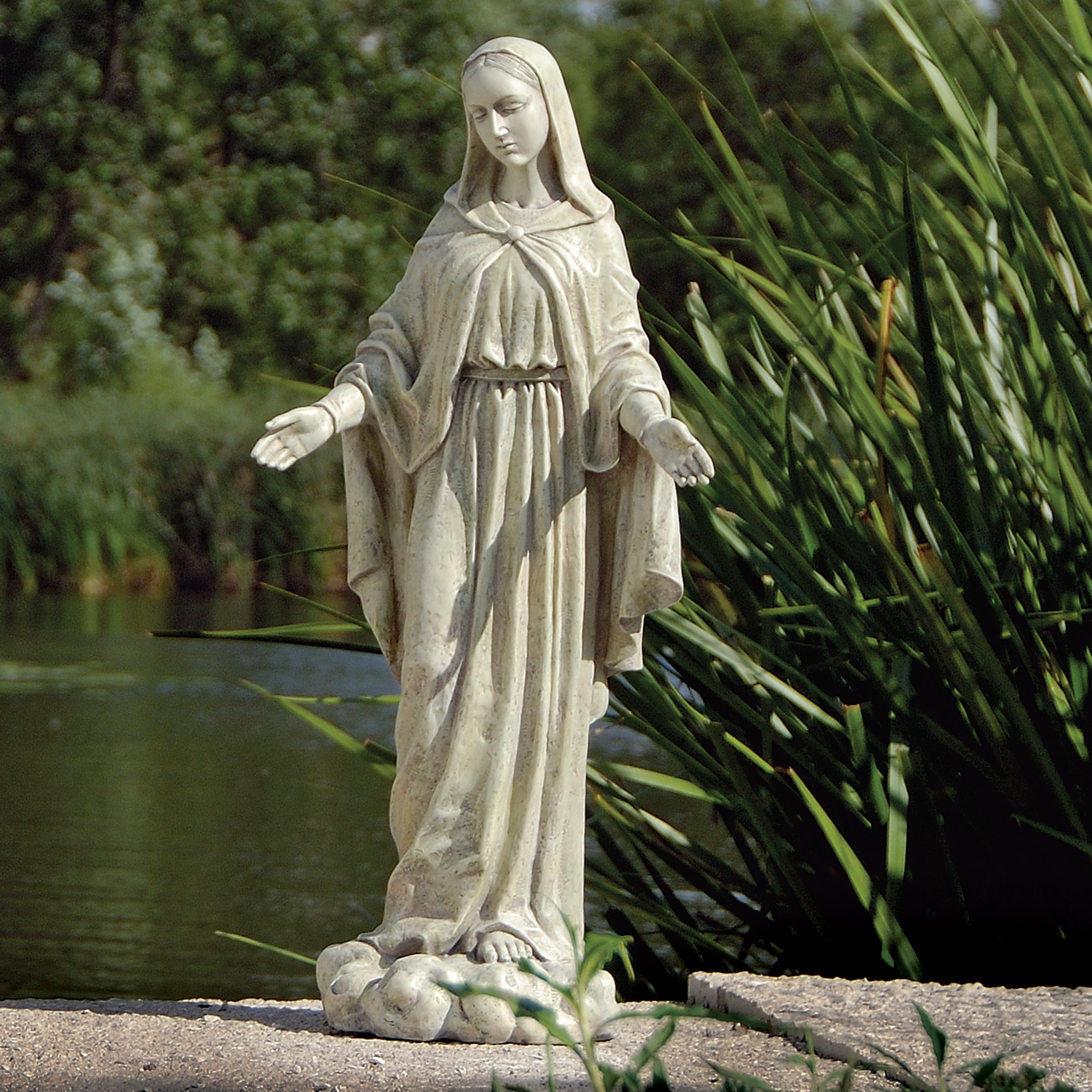 Statue of a draped figure in a garden setting with greenery