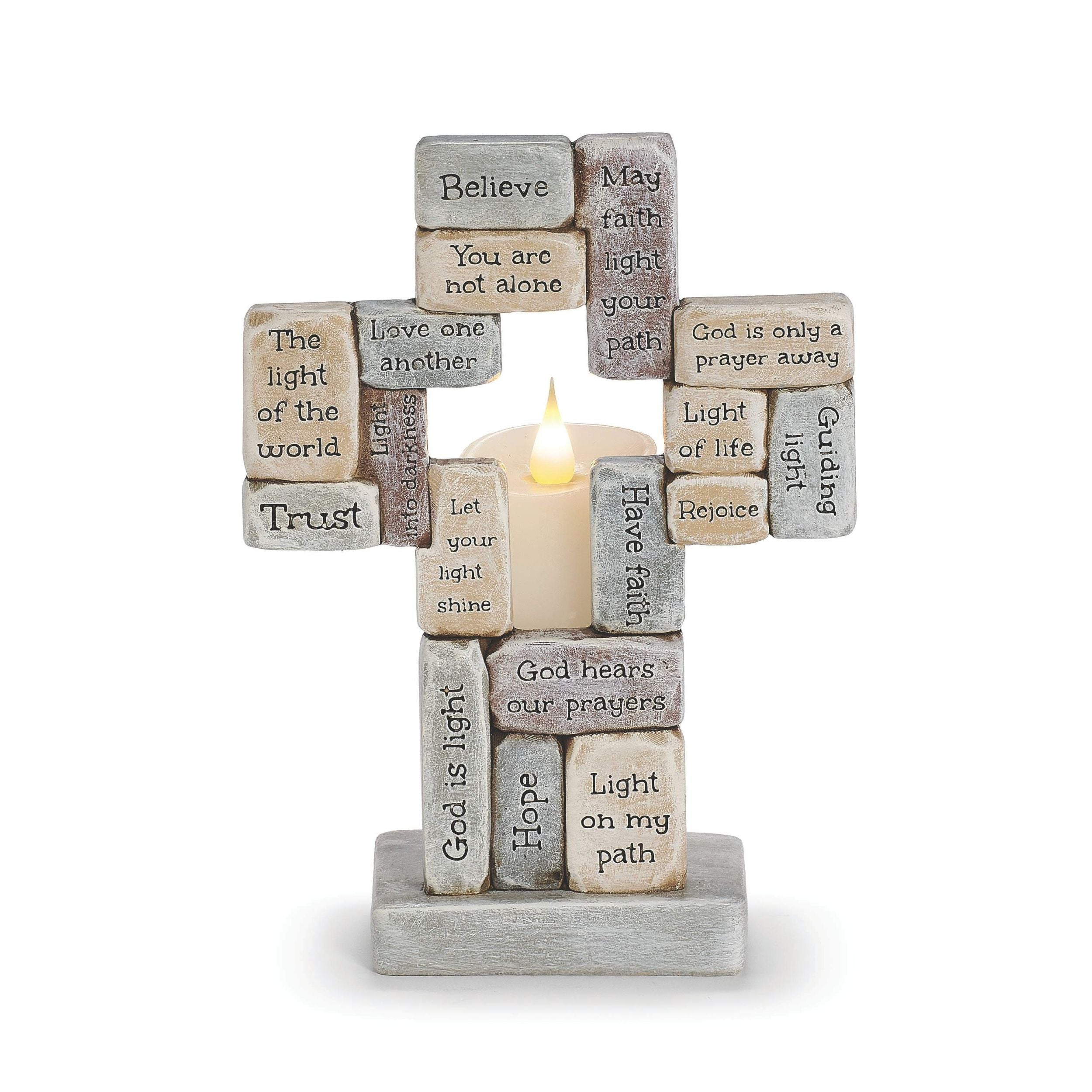 Decorative cross made of engraved stones with a candle at the center on a white background