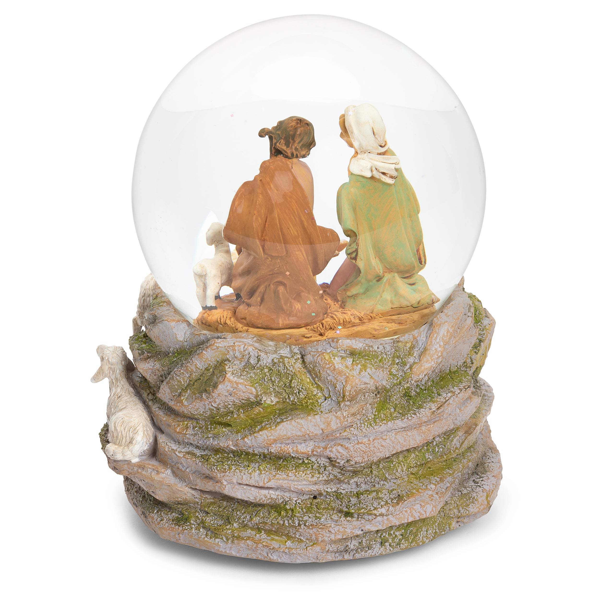 A nativity scene snow globe figurine featuring Mary, Joseph, baby Jesus, and a small white sheep inside a clear glass globe, set on a textured rocky base with a white goat.