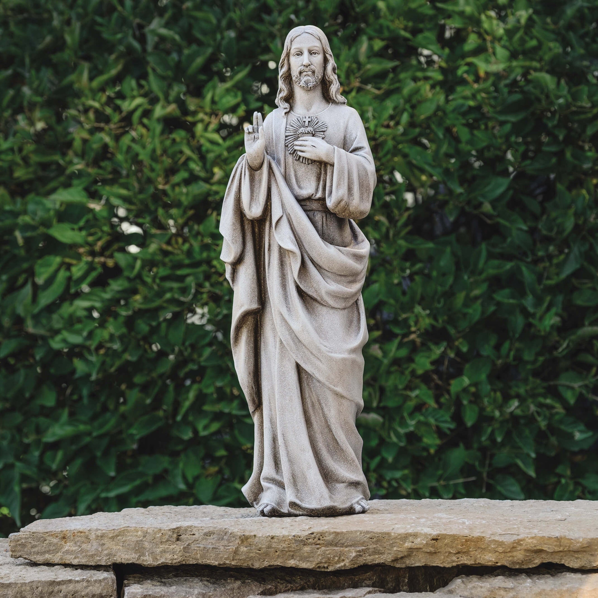 Statue of a religious figure in a natural setting with greenery