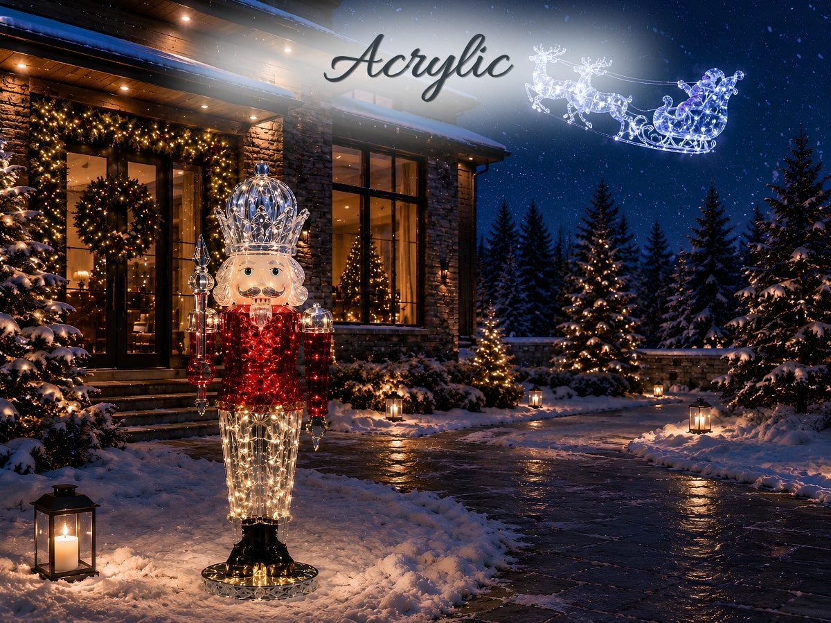 A large acrylic nutcracker Christmas light decoration stands in a snowy front yard at night, with a lit sleigh of stars above and holiday trees and house lights in the background. The word 'Acrylic' appears at the top.