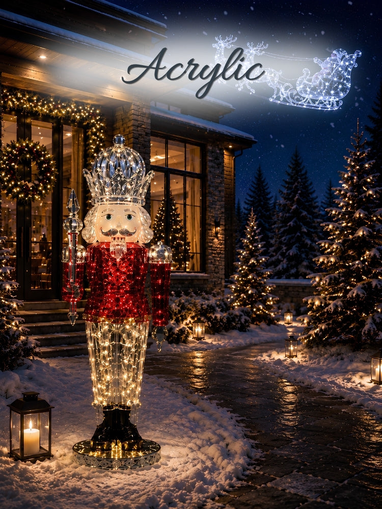 A large acrylic nutcracker holiday decoration stands in a snowy front yard at night, illuminated with warm white lights and accented with red glitter. Christmas trees, lanterns, and a house with holiday garlands are visible in the background, with the word 'Acrylic' and a snowflake logo overlaid at the top.