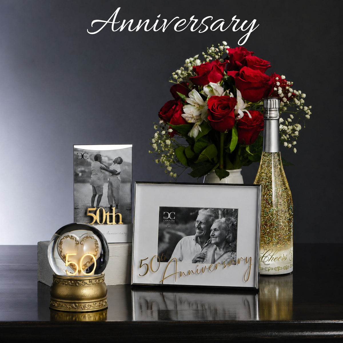 50th Anniversary celebration set with flowers, photo frame, and sparkling wine bottle on a dark surface.