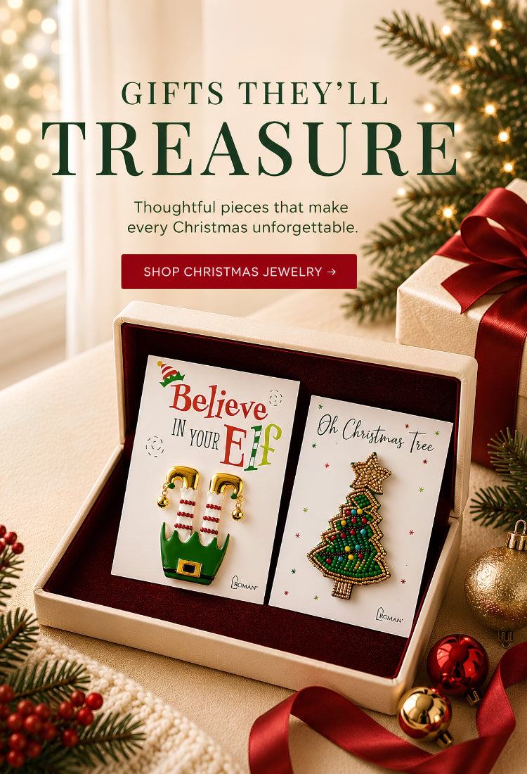 A Christmas-themed gift set displayed in an open beige box with a dark red interior. The set includes two enamel pins: one featuring green elf boots with the text 'Believe in your Elf' and another featuring a green Christmas tree with the text 'Oh Christmas Tree'.