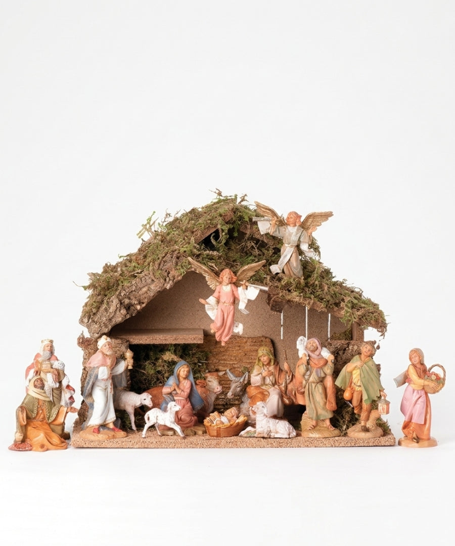 A multi-piece Christmas nativity scene figurine set featuring Mary, Joseph, baby Jesus, angels, shepherds, and animals inside a rustic stable with a mossy roof, set against a plain white background.