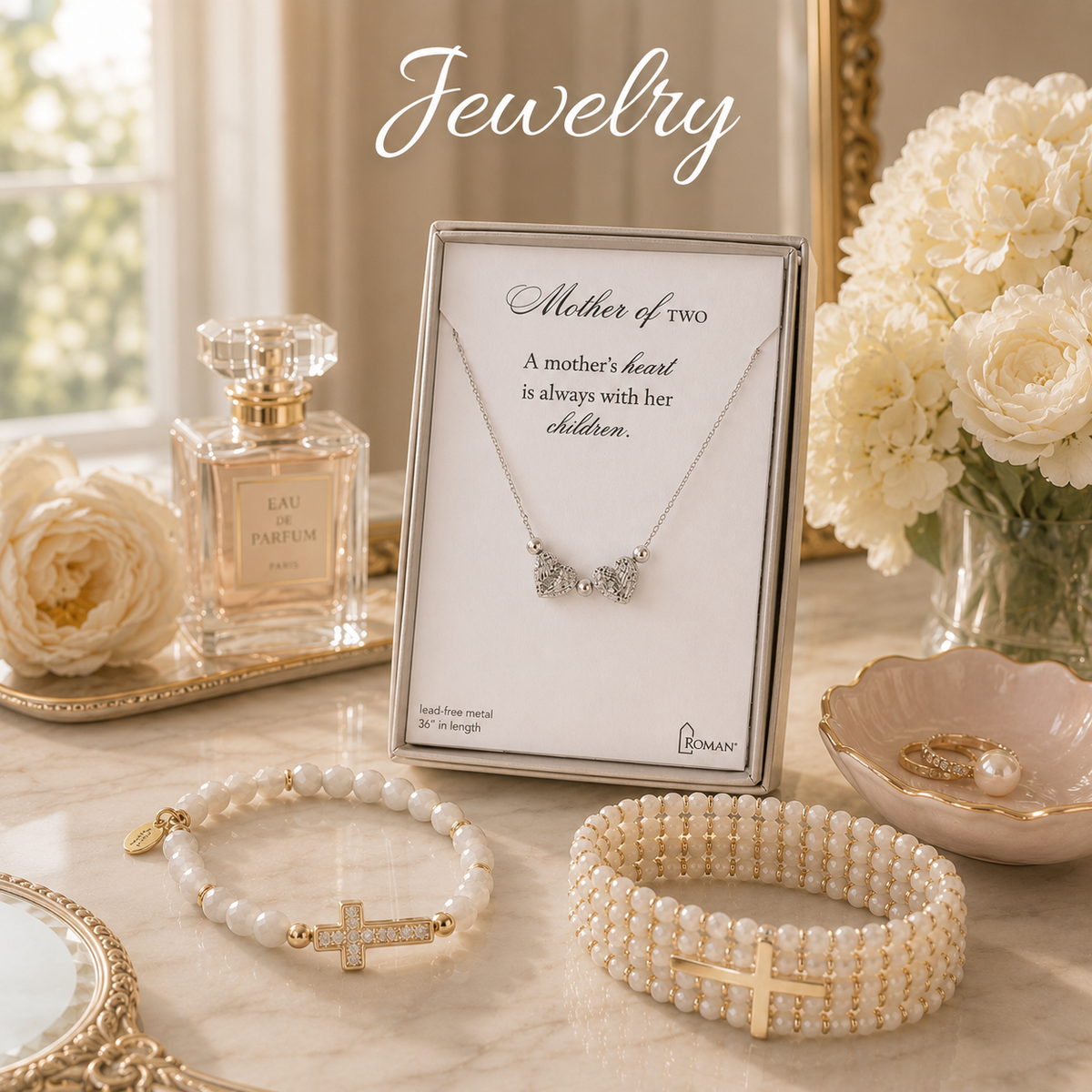A jewelry display on a marble surface featuring a boxed necklace for 'Mother of two' with a small silver-toned double-heart pendant, alongside pearl-style bracelets with gold-tone cross and oval charms, flowers, a perfume bottle, and decorative mirrors in a softly styled interior setting.