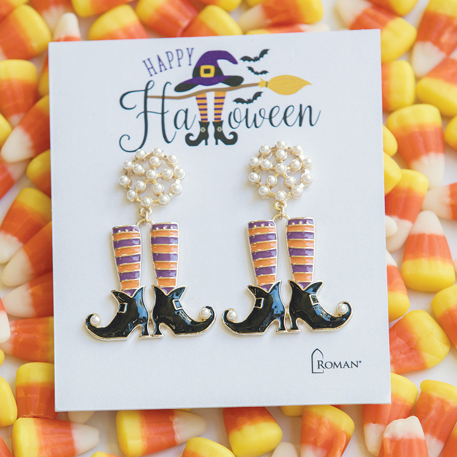 Witch boot earrings with striped socks and pearl accents on a candy corn background