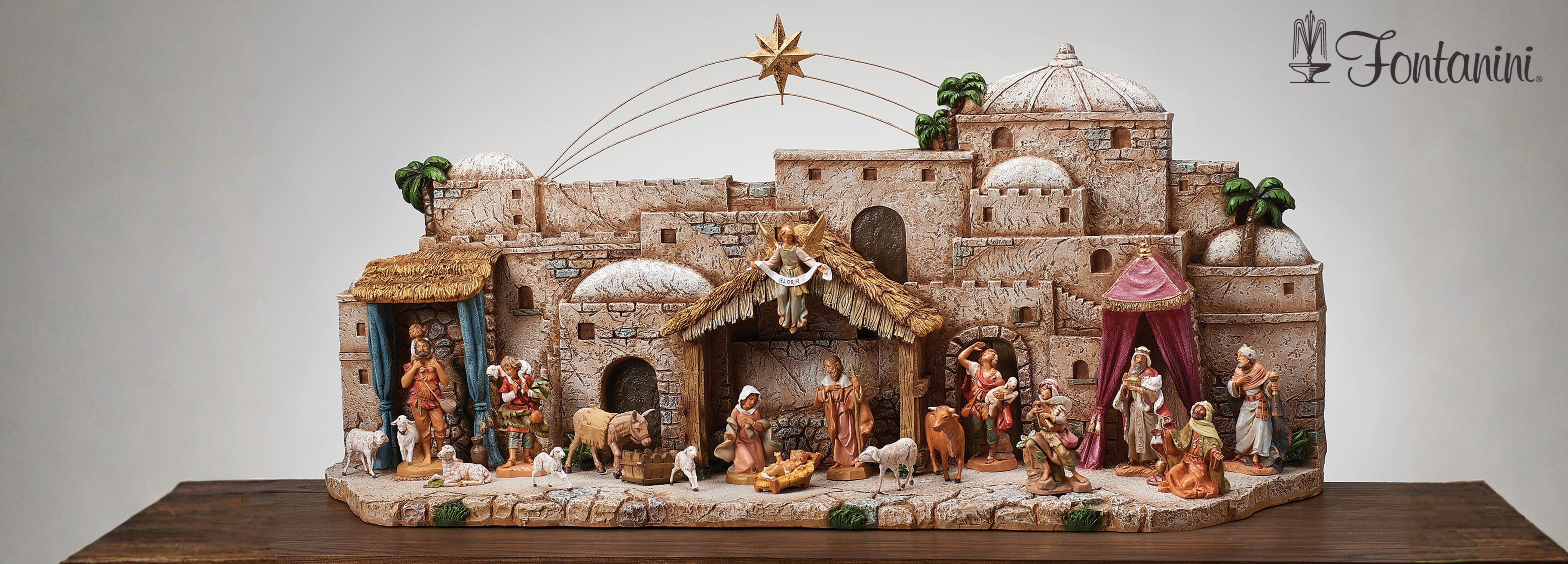 Fontanini nativity scene display featuring detailed buildings, Holy Family, and figurines set against a white background.