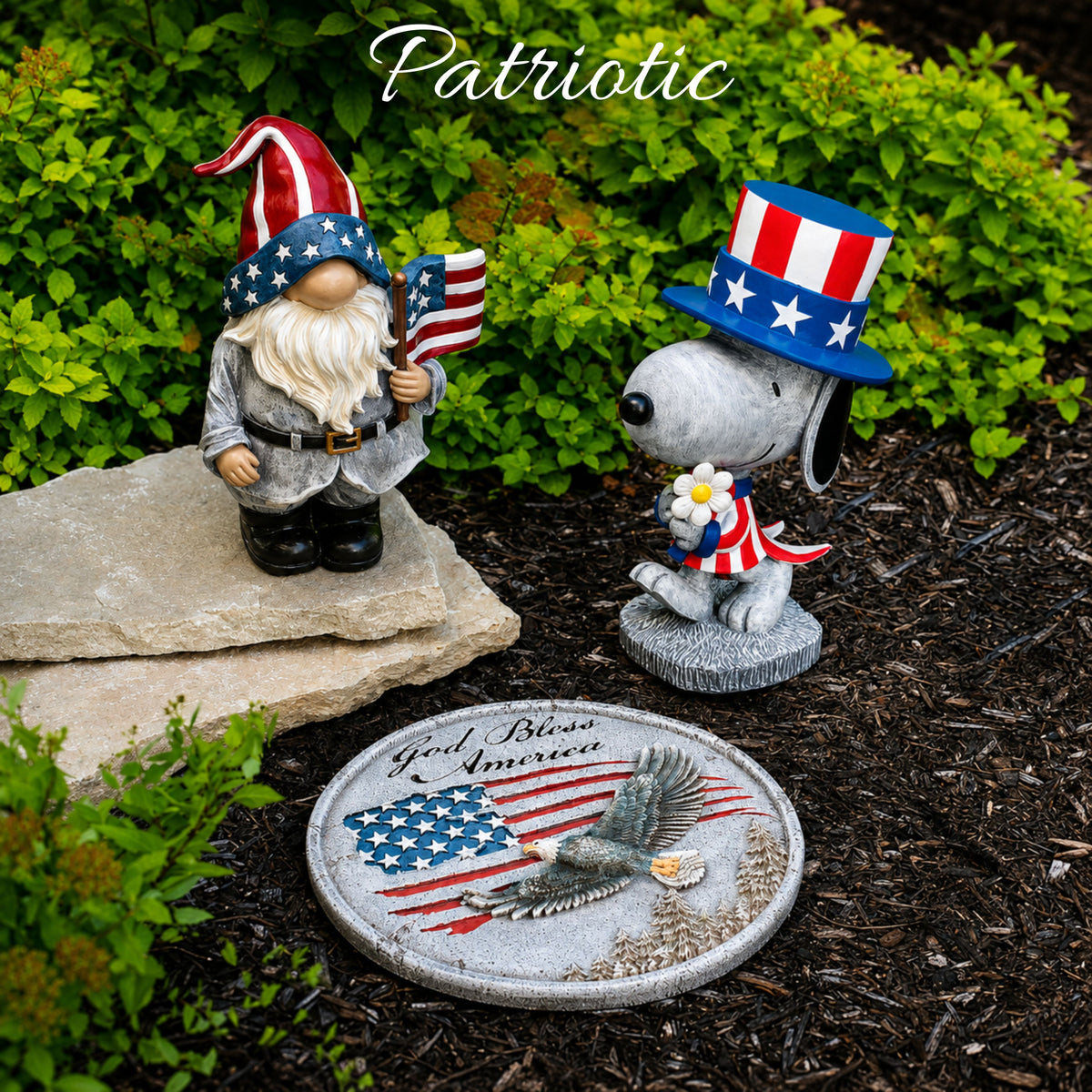 Two garden gnome figurines with American flag hats and a dog figurine holding a flower, standing on a stone with 'God Bless America' and an eagle design.