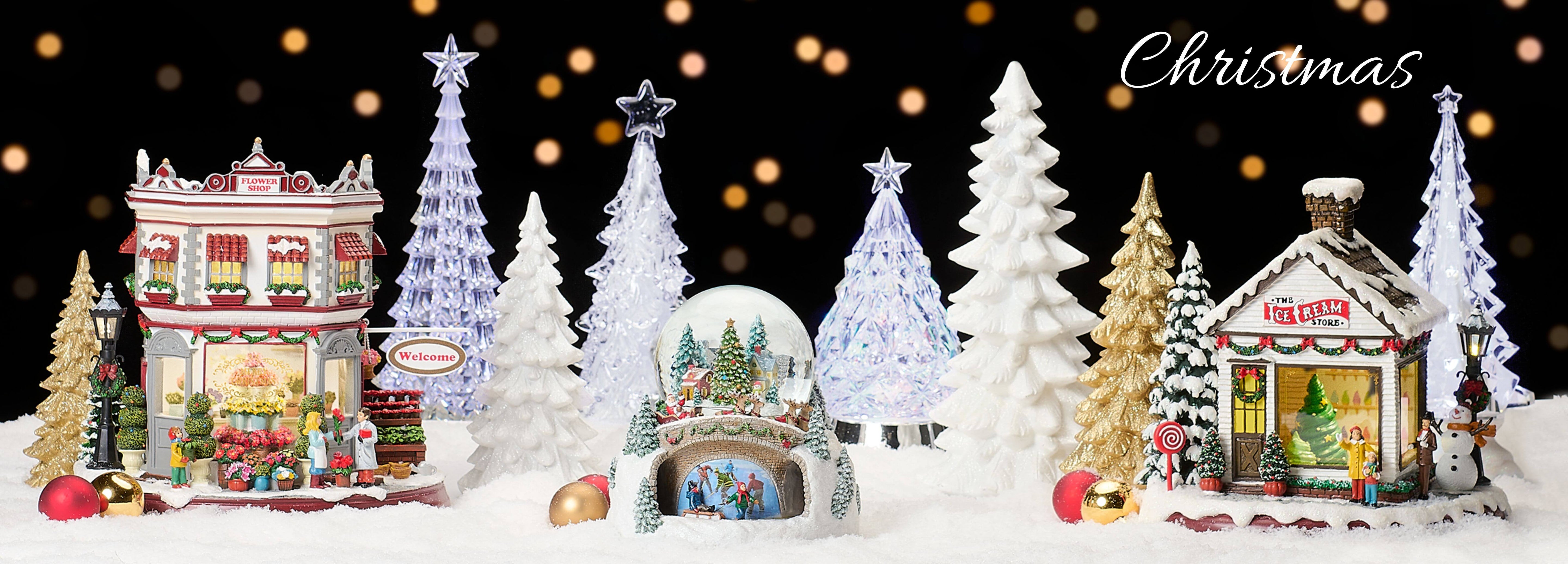 Roman Christmas Village display featuring lighted buildings, snowy trees, and festive holiday décor under a warm glowing background.